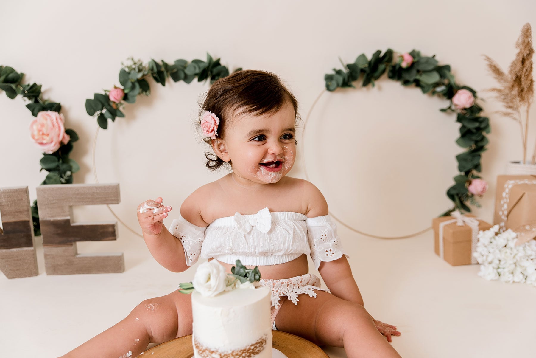 Picture of a baby with a white cake and frosting on her face