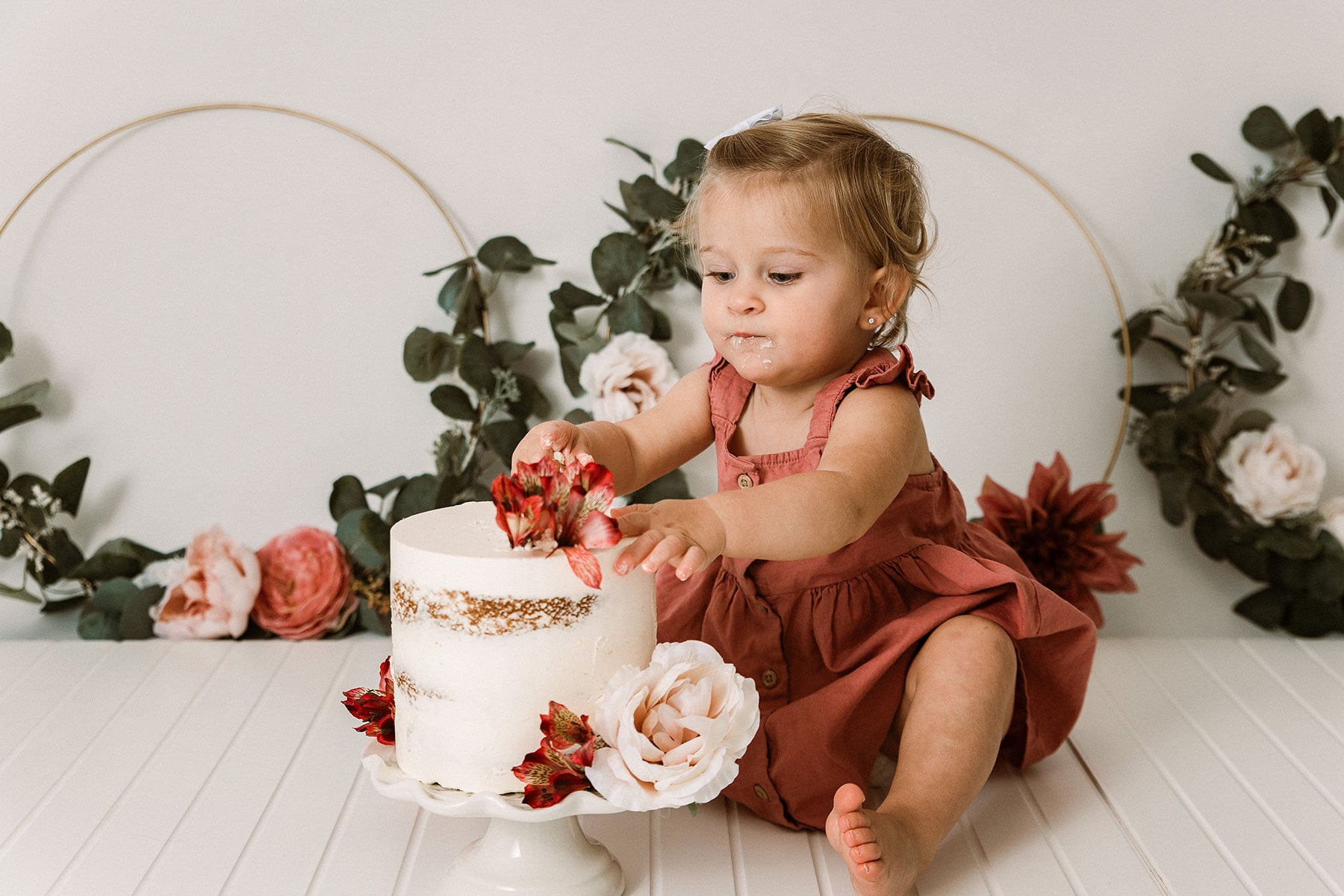 Picture of a baby with a white cake and frosting on her face