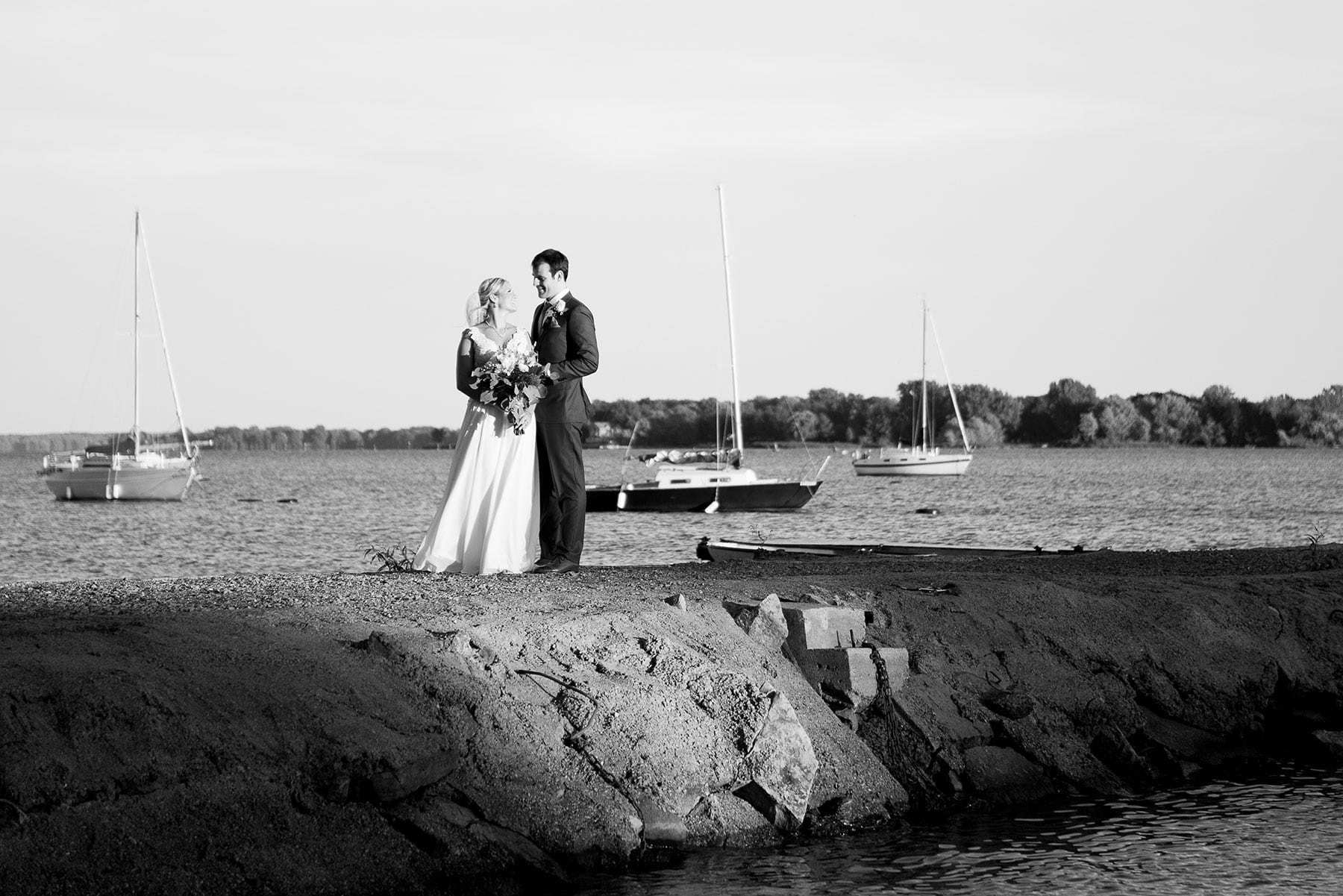 Black and white image of a newlywed couple standing on a rock